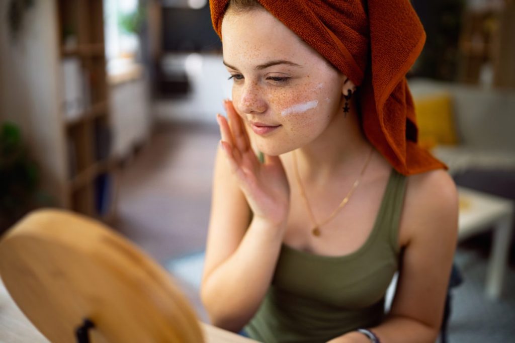 Girl applying moisturizer as part of winter skincare
